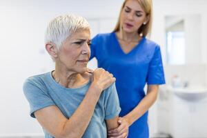 Doctor or Physiotherapist working examining treating injured arm of senior patient, stretching and exercise, Doing the Rehabilitation therapy pain in clinic. photo