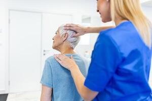 Licensed chiropractor or manual therapist doing neck stretch massage to relaxed female patient in clinic office. Young woman with whiplash or rheumatological problem getting professional doctor's help photo