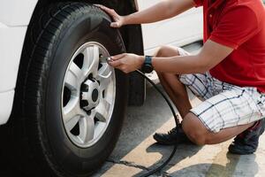 A man is sitting on the ground and inflating a tire with a tire inflator photo