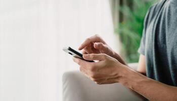 A man is holding a cell phone and is looking at it photo