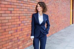 Portrait of a successful business woman in front of modern business building. Young manager poses outside. Female business leader photo