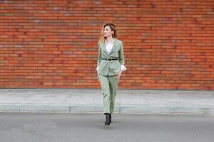 Portrait of a successful business woman in front of modern business building. Young manager poses outside. Female business leader. photo