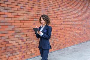 Portrait of a successful business woman in front of modern business building. Young manager poses outside. Female business leader photo