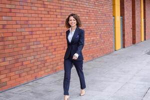 Portrait of a successful business woman in front of modern business building. Young manager poses outside. Female business leader photo