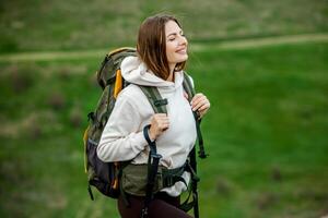 Young woman with backpack hiking in the mountains. Hiking concept. Trekking cliffs. Travel, traveler. photo