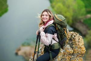 Young woman with backpack hiking in the mountains. Hiking concept. Trekking cliffs. Travel, traveler. photo