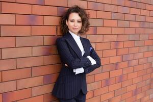 Portrait of a successful business woman in front of modern business building. Young manager poses outside. Female business leader photo