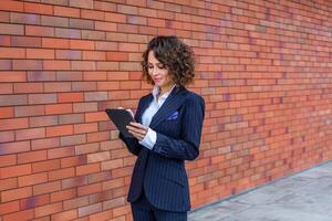 Portrait of a successful business woman in front of modern business building. Young manager poses outside. Female business leader photo