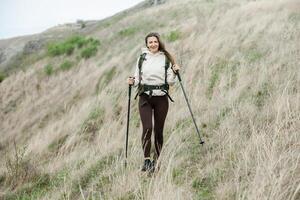 Young woman with backpack hiking in the mountains. Hiking concept. Trekking cliffs. Travel, traveler. photo