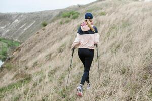 Young woman with backpack hiking in the mountains. Hiking concept. Trekking cliffs. Travel, traveler. photo