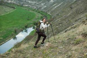 Young woman with backpack hiking in the mountains. Hiking concept. Trekking cliffs. Travel, traveler. photo