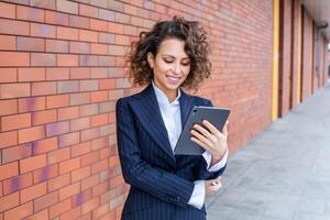 Portrait of a successful business woman in front of modern business building. Young manager poses outside. Female business leader photo