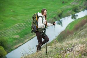 Young woman with backpack hiking in the mountains. Hiking concept. Trekking cliffs. Travel, traveler. photo