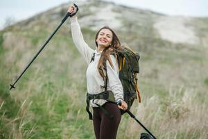 Young woman with backpack hiking in the mountains. Hiking concept. Trekking cliffs. Travel, traveler. photo