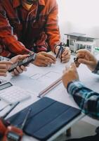 engineer people meeting working and pointing at a drawings in office for discussing. Engineering tools and construction concept. photo