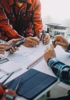 ingeniero personas reunión trabajando y señalando a un dibujos en oficina para que se discute. Ingenieria herramientas y construcción concepto. foto