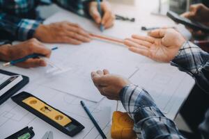 engineer people meeting working and pointing at a drawings in office for discussing. Engineering tools and construction concept. photo