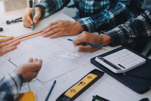 engineer people meeting working and pointing at a drawings in office for discussing. Engineering tools and construction concept. photo