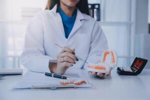 los dentistas están discutiendo problemas dentales al informar la imagen de rayos X en la pantalla del portátil a los pacientes. foto