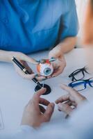 de cerca de asiático hembra médico hablando con mayor paciente demostración globo ocular modelo y explicando ojo enfermedad en hospital foto