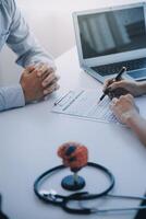 Doctor explaining brain functions to patient on model in office. photo