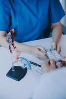 Doctor uses anatomical model to explain male urinary system. Model labeled with parts, doctor points and explains how they work together for urinary function, ensuring patient comprehension. photo