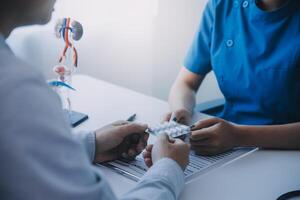 Doctor uses anatomical model to explain male urinary system. Model labeled with parts, doctor points and explains how they work together for urinary function, ensuring patient comprehension. photo