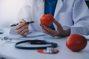 Doctor explaining heart to elderly patient. Doctor explaining the heart model. Doctors pen point to a model of the heart photo