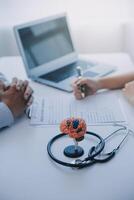 Doctor explaining brain functions to patient on model in office. photo