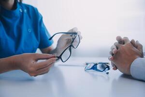 Close-up of Asian female doctor talking with elderly patient showing eyeball model and explaining eye disease in hospital photo