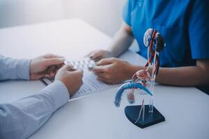 Doctor uses anatomical model to explain male urinary system. Model labeled with parts, doctor points and explains how they work together for urinary function, ensuring patient comprehension. photo