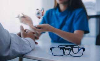 Close-up of Asian female doctor talking with elderly patient showing eyeball model and explaining eye disease in hospital photo