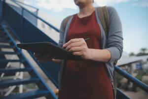 rubia hembra turista comprobación entrante notificación en teléfono inteligente sentado en asiento de avión con netbook.joven mujer de negocios compartir medios de comunicación desde teléfono en ordenador portátil computadora durante avión vuelo foto