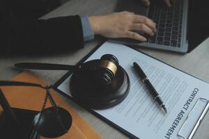 Business and lawyers discussing contract papers with brass scale on desk in office. Law, legal services, advice, justice and law concept picture with film grain effect photo