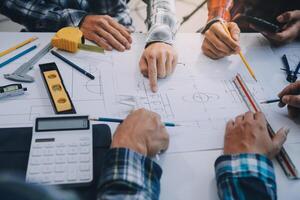 engineer people meeting working and pointing at a drawings in office for discussing. Engineering tools and construction concept. photo