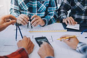 engineer people meeting working and pointing at a drawings in office for discussing. Engineering tools and construction concept. photo