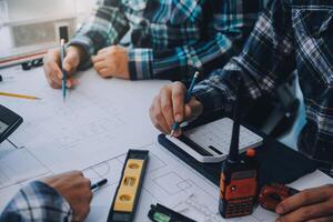 engineer people meeting working and pointing at a drawings in office for discussing. Engineering tools and construction concept. photo