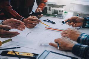 engineer people meeting working and pointing at a drawings in office for discussing. Engineering tools and construction concept. photo