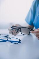 Close-up of Asian female doctor talking with elderly patient showing eyeball model and explaining eye disease in hospital photo