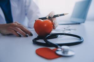 Doctor explaining heart to elderly patient. Doctor explaining the heart model. Doctors pen point to a model of the heart photo