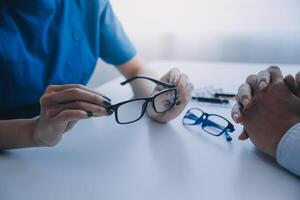 Close-up of Asian female doctor talking with elderly patient showing eyeball model and explaining eye disease in hospital photo