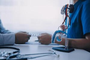 Doctor uses anatomical model to explain male urinary system. Model labeled with parts, doctor points and explains how they work together for urinary function, ensuring patient comprehension. photo