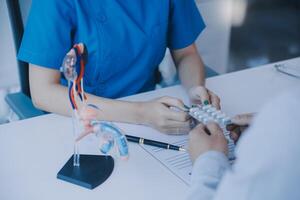 Doctor uses anatomical model to explain male urinary system. Model labeled with parts, doctor points and explains how they work together for urinary function, ensuring patient comprehension. photo