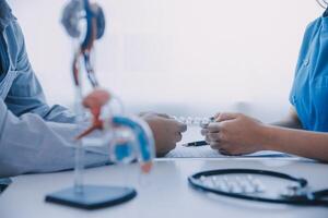 Doctor uses anatomical model to explain male urinary system. Model labeled with parts, doctor points and explains how they work together for urinary function, ensuring patient comprehension. photo