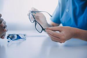 Close-up of Asian female doctor talking with elderly patient showing eyeball model and explaining eye disease in hospital photo