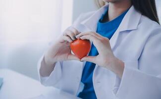 Doctor explaining heart to elderly patient. Doctor explaining the heart model. Doctors pen point to a model of the heart photo