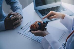 Doctor explaining heart to elderly patient. Doctor explaining the heart model. Doctors pen point to a model of the heart photo