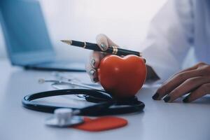 Doctor explaining heart to elderly patient. Doctor explaining the heart model. Doctors pen point to a model of the heart photo