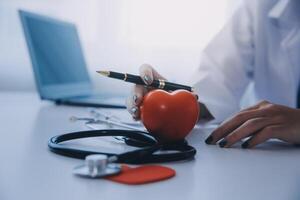 Doctor explaining heart to elderly patient. Doctor explaining the heart model. Doctors pen point to a model of the heart photo