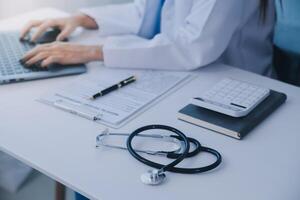 médico y paciente sentado a el escritorio en clínica oficina. el atención es en hembra médico manos relleno arriba el medicación historia grabar forma, cerca arriba. medicina concepto foto